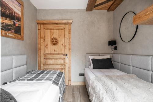 a bedroom with two beds and a wooden door at ZAKOZNAMI-WILLA WYPAS-APARTAMENT B3 in Zakopane