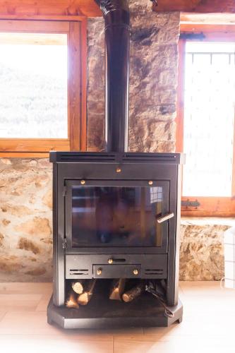 a black stove in a room with a stone wall at Casa rústica la Borda de la Munda. in Arsèguel