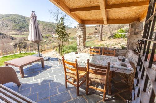a patio with a table and chairs and an umbrella at Casa rústica la Borda de la Munda. in Arsèguel
