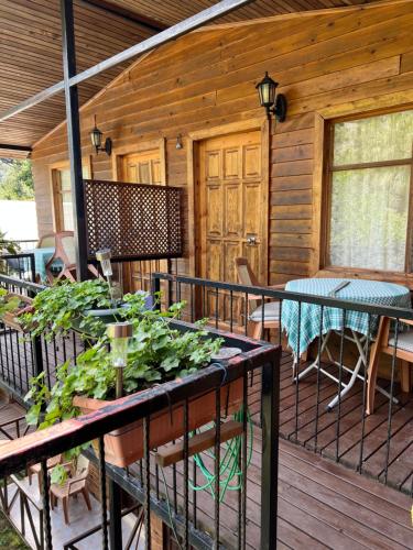 un porche de una cabaña de madera con una mesa con plantas en Oran Ağaç Bungalovs, en Kemer