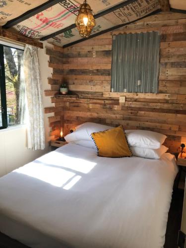 a bedroom with a large white bed with a wooden wall at The Vobster Inn in Radstock