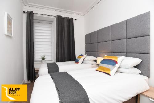 Duas camas num quarto com lençóis e almofadas brancos em Baxter Park - City Base em Dundee