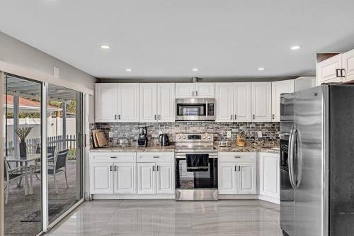 a kitchen with white cabinets and a stainless steel refrigerator at Modern Villa with Pool Hollywood Hard Rock Casino in Fort Lauderdale