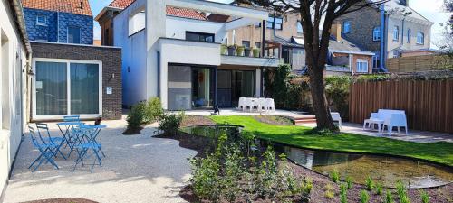 a house with a table and chairs in a yard at B&B Charles Cabour in De Panne