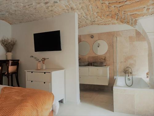 um quarto com uma cama, uma banheira e uma televisão em La Cachette em Aigues-Vives