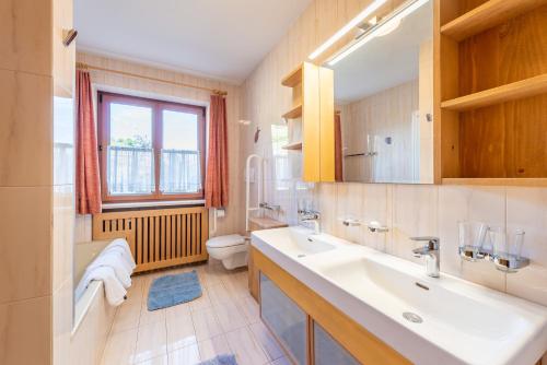 a bathroom with a sink and a toilet and a window at Haus Bellutti in Termeno