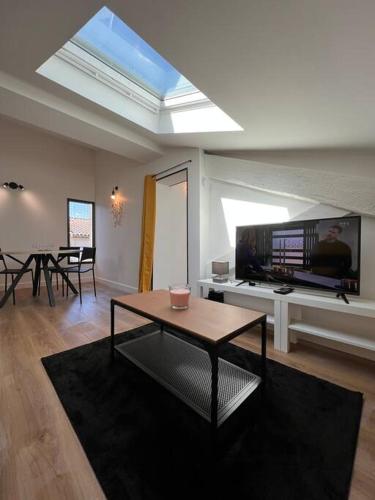 Il comprend un salon doté d'une table et d'une télévision à écran plat. dans l'établissement Le Belfort - Grand T2 climatisé en hyper centre, à Toulouse