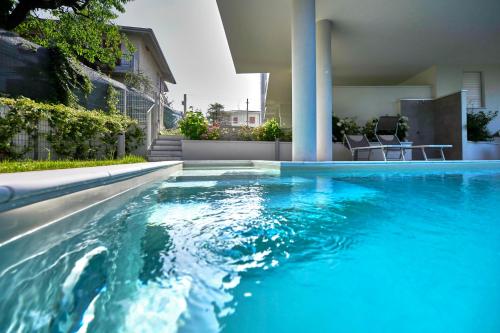 a swimming pool with blue water in front of a house at ApartmentsGarda - Le Terrazze Del Garda Residence in Lazise