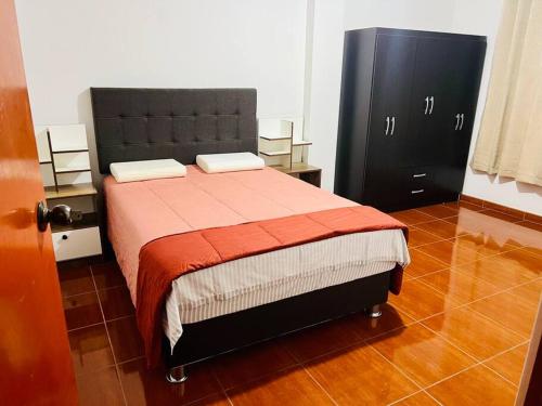 a bedroom with a bed and a black cabinet at Departamento Amplio Pérez Gamboa in Tacna