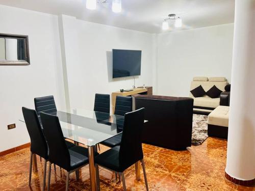Departamento Amplio Pérez Gamboa في تاكنا: غرفة طعام مع طاولة زجاجية وكراسي سوداء