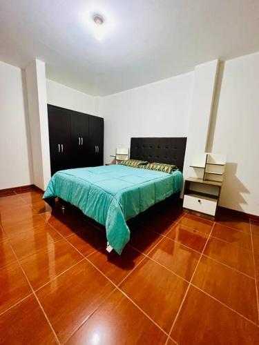 1 dormitorio con 1 cama y suelo de madera en Departamento Amplio Pérez Gamboa, en Tacna