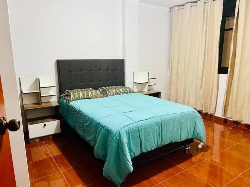 1 dormitorio con 1 cama grande con manta azul en Departamento Amplio Pérez Gamboa, en Tacna