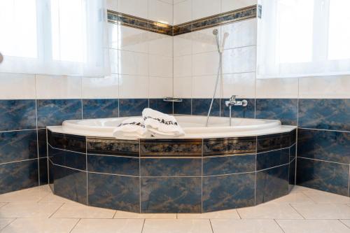 a bath tub in a bathroom with blue tiles at Schlafen zur Brauerei St. Johann in Nesslau