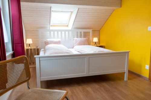 a white bed in a room with yellow walls at Schlafen zur Brauerei St. Johann in Nesslau