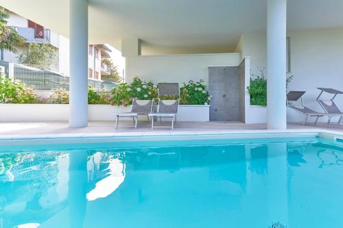 a swimming pool with two chairs next to a building at ApartmentsGarda - Le Terrazze Del Garda Residence in Lazise