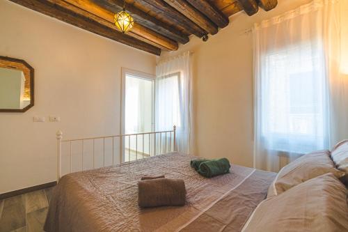 a bedroom with a large bed and two windows at Casetta Stretta Bersaglio in Chioggia