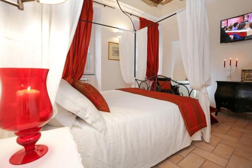 Un dormitorio con una cama roja y blanca con una vela en Madonna de' Monti Suites, en Roma