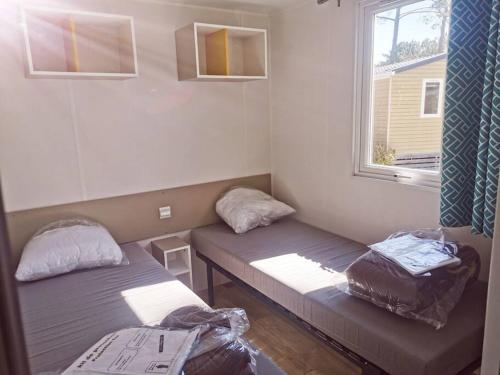 um quarto com duas camas e uma janela em Mobil home Premium Camping 5* em Vendays-Montalivet