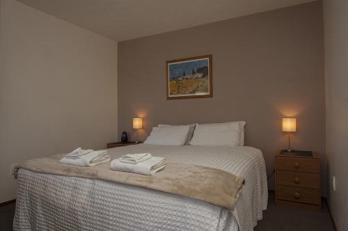 een slaapkamer met een bed met twee handdoeken erop bij Garden City Motel in Christchurch