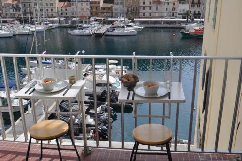 uma varanda com uma mesa e 2 cadeiras e uma marina em Appartement duplex plein sud sur le port de Bonifacio em Bonifacio