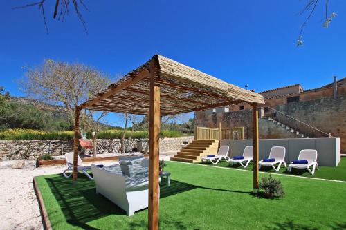 a wooden gazebo with chairs and a lawn at Villa Son Pons by Slow Villas in Llucmajor