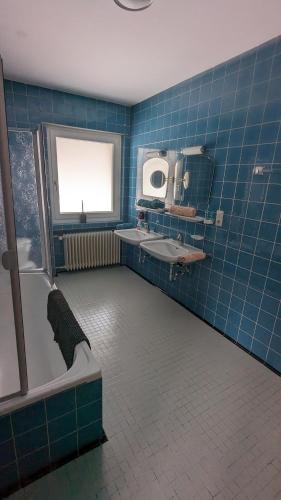 a blue tiled bathroom with a tub and a sink at Landhaus Steinbrech in Grainau