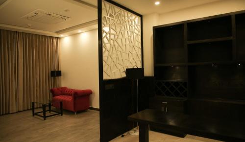 a living room with a red chair and a table at Rosetum Kasauli in Kasauli