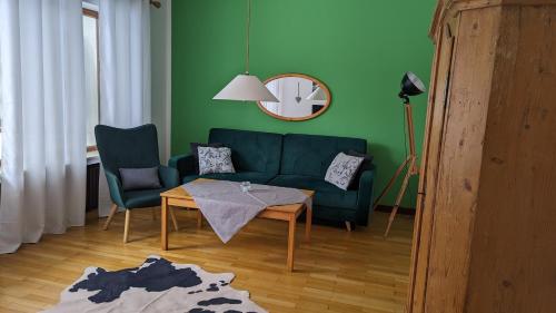 a living room with a green couch and a table at Landhaus Steinbrech in Grainau