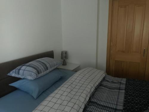 Schlafzimmer mit einem Bett mit einem Kissen und einer Tür in der Unterkunft Lovely 1-Bed Cottage in Hopeman in Elgin