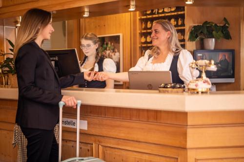 zwei Frauen, die in einer Bar stehen und mit einem Kunden reden in der Unterkunft Hotel & Restaurant Zum Reussenstein in Böblingen