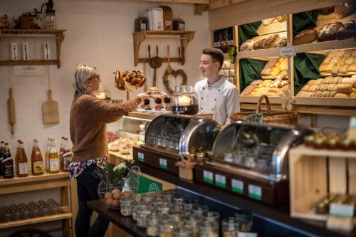 ベーブリンゲンにあるHotel & Restaurant Zum Reussensteinのパン屋のカウンターの後ろに立つ女