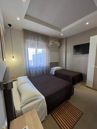 a hotel room with two beds and a table at Hotel Europa Parking in Livorno