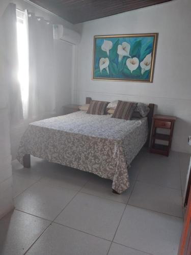 a bedroom with a bed and a painting on the wall at Apartamento na Passarela in Porto Seguro