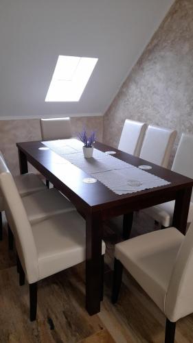 a dining room table with white chairs and a skylight at Kincsem Vendégház in Szilvásvárad