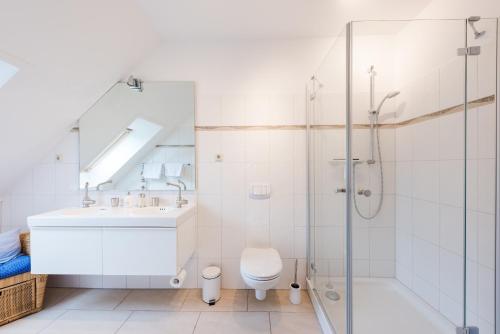 a bathroom with a shower and a sink and a toilet at Landhaus Greetsiel am Hafen "Kapitänsbrücke II" in Krummhörn