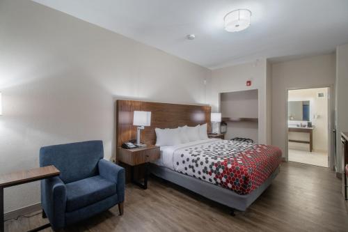 a bedroom with a bed and a blue chair at Econo Lodge Inn & Suites Foley-North Gulf Shores in Foley