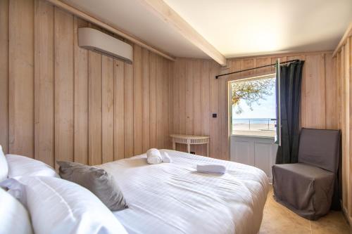 a bedroom with a bed and a chair and a window at Villa Les Délices in Cap-Ferret
