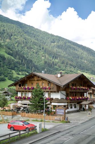 a building with a red car parked in front of it at Hotel Brunnenhof in Neustift im Stubaital