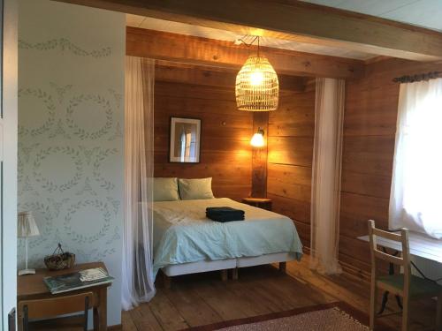 a bedroom with a bed with a wooden wall at La Maison Rouge de Slätten Bed and Breakfast in Vilshult