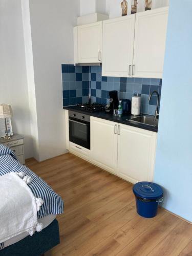 una pequeña cocina con armarios blancos y suelo de madera. en Hendrika Apartments, en Zandvoort