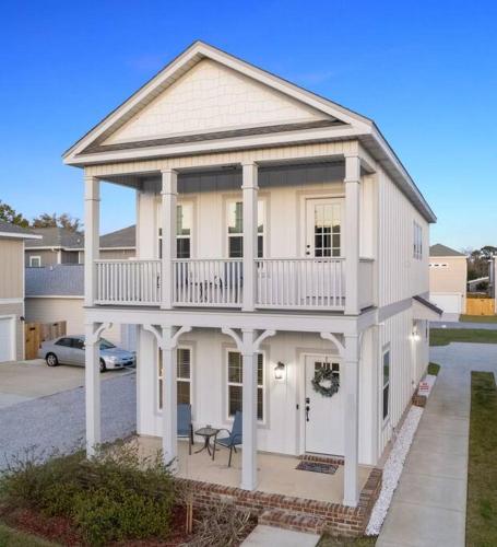 a large white house with a balcony on top at Cheerful 3BR close to downtown + double balcony in Pensacola