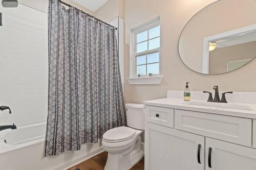 ein Badezimmer mit einem WC, einem Waschbecken und einem Spiegel in der Unterkunft Cheerful 3BR close to downtown + double balcony in Pensacola