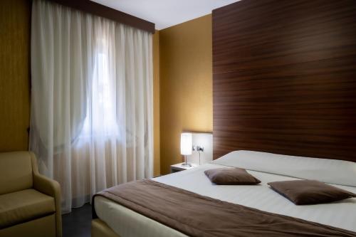 a bedroom with a bed and a chair and a window at Hotel Premiere in Marina di Varcaturo