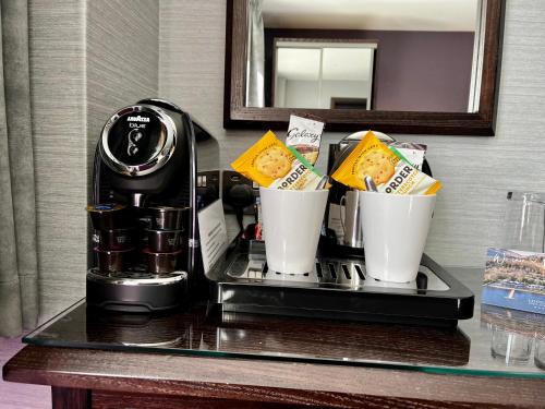a coffee maker and cups on a table in a hotel room at The Beach House Loch Lomond in Luss