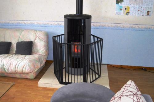 Gite LA ROCHERIE في Hambers: مدفأة سوداء في غرفة المعيشة مع أريكة