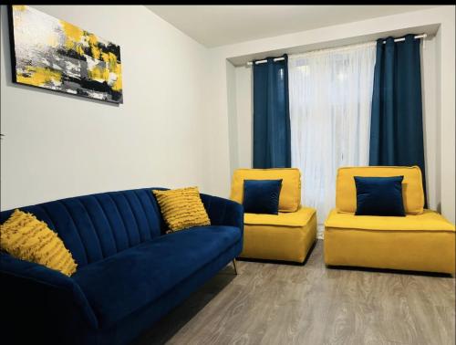 a living room with a blue couch and two yellow chairs at Fantastique 3 chambres modernes au cœur de la ville in Montréal