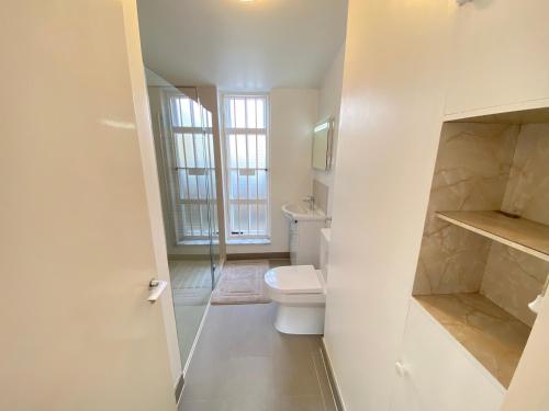 uma casa de banho branca com um WC e uma janela em Cosy duplex in Central London em Londres