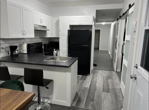 cocina con armarios blancos y nevera negra en Fantastique 3 chambres modernes au cœur de la ville en Montreal