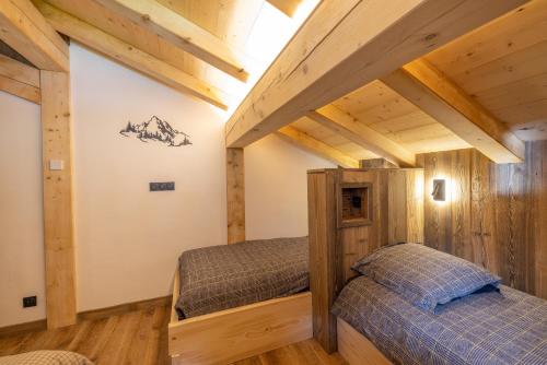 two beds in a room with wooden ceilings at Chalet Quartz in Saint-Gervais-les-Bains