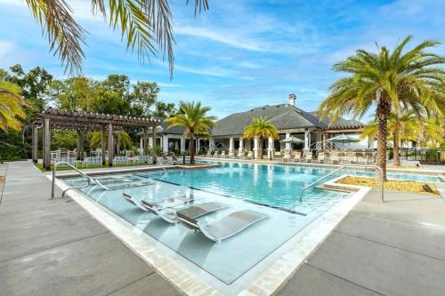 an image of a swimming pool with palm trees and a house at Chic 1 and 2 Bedroom Apartments at Vintage Amelia Island next to Fernandina Beach in Fernandina Beach